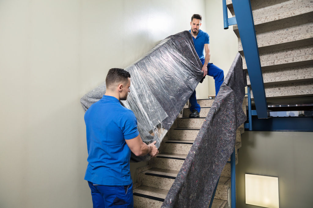 Movers hauling couch up flight of stairs